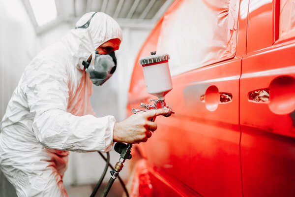 Close up details of mechanic worker, painting a red car