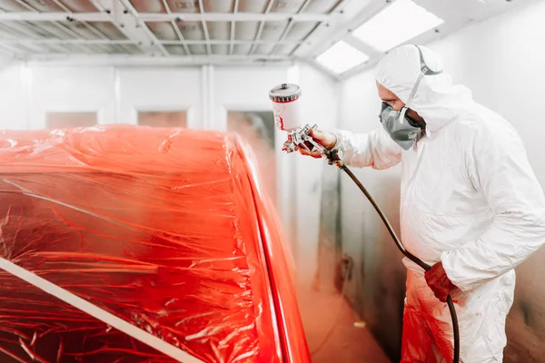 Ingeniero de la industria automotriz con pistola de pulverización y pintura de un coche rojo — Foto de Stock