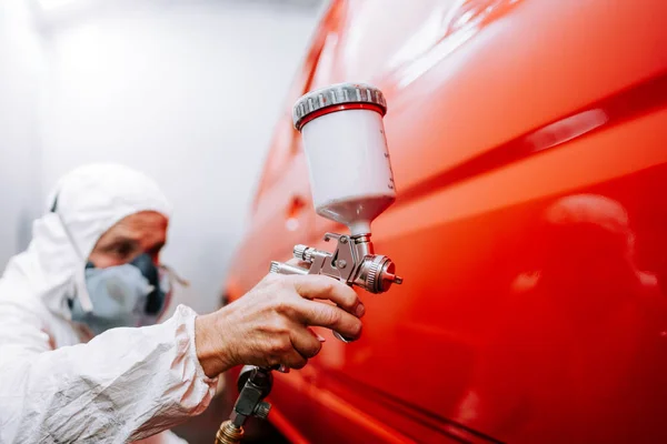 Trabajador mecánico pintando un coche en una caja de pintura especial, con un traje de cuerpo completo y equipo de protección —  Fotos de Stock