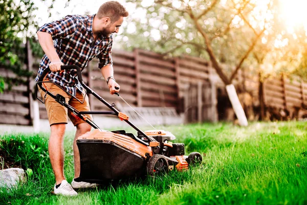 Detalhes jardinagem, jardineiro industrial começando o cortador de grama e cortar grama em garde — Fotografia de Stock