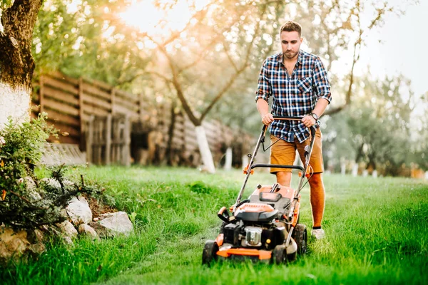 Garden and grass maintainance details - close up view of grass mower and worker — Stock Photo, Image