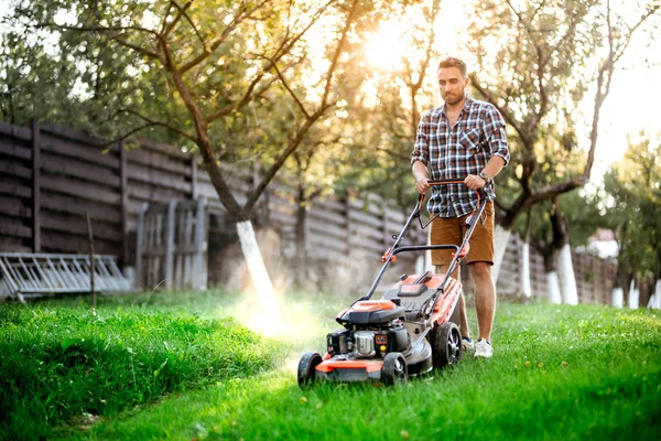 Détails de jardinage, jardinier industriel travaillant avec tondeuse à gazon et couper l'herbe dans la cour arrière — Photo