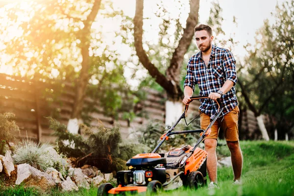 Lavoratore tagliare l'erba con tosaerba e strumenti professionali — Foto Stock