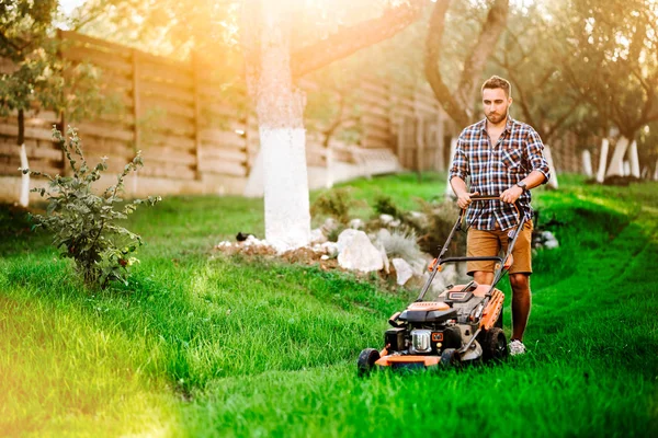 Retrato de jardinero profesional usando cortacésped y cortando hierba durante el atardecer de verano —  Fotos de Stock