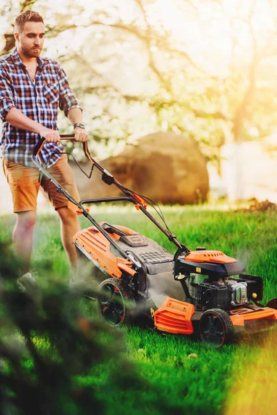Retrato de trabajador de jardinero guapo usando cortacésped y cortando la hierba del jardín —  Fotos de Stock