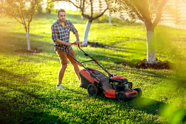 Jardineiro cortando o gramado usando um dispositivo alimentado a gasolina, um cortador de grama profissional — Fotografia de Stock