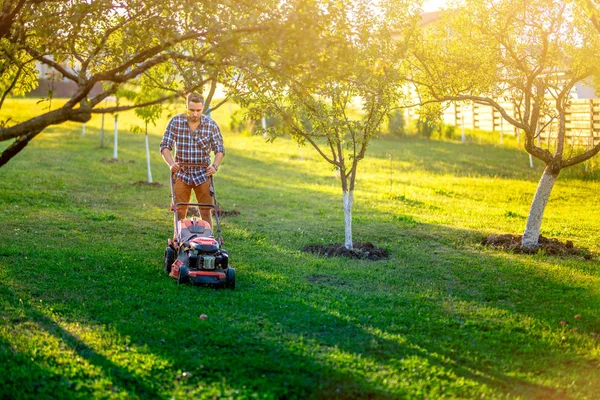 Jardinería y mantenimiento del jardín, jardinero casero usando cortacésped y cortando hierba en el jardín — Foto de Stock