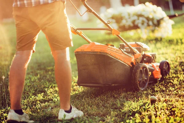 산업 원예 및 조경의 일몰 세부 사항. 여름 철에 잔디 깎는 기계와 잔디를 자르는 백인 정원사 — 스톡 사진