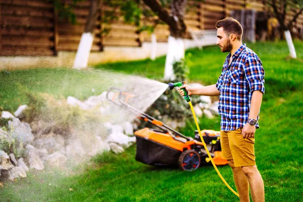 Close up of smiling man watering backyard lawn using hose. Irrigation system — Stock Photo, Image