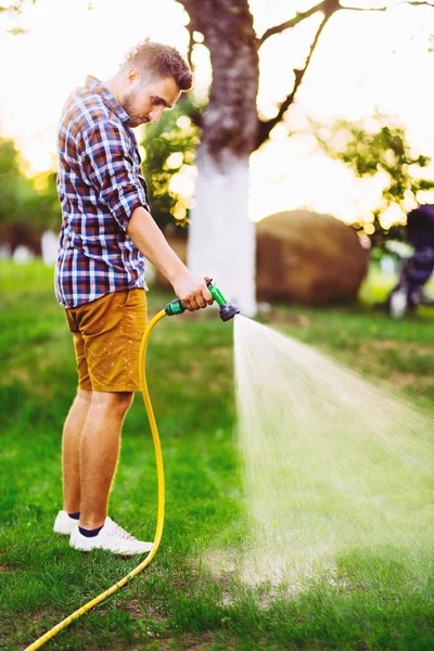 Jardinero profesional que trabaja en el jardín, utilizando mangueras y plantas de riego —  Fotos de Stock