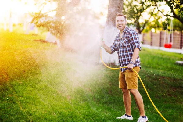 Detalles de jardinería - hombre jugando con la manguera y el riego del césped —  Fotos de Stock