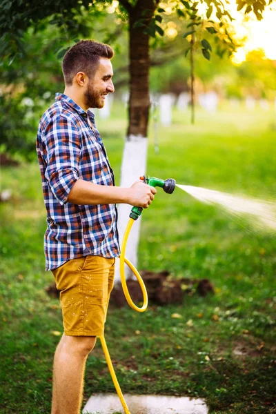 Fermer les détails du jardinier à l'aide d'un tuyau d'arrosage et arroser la pelouse, l'herbe et les plantes. jardinage arrière-cour — Photo