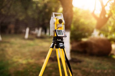 surveyor engineering equipment with theodolite and total station in a garden clipart