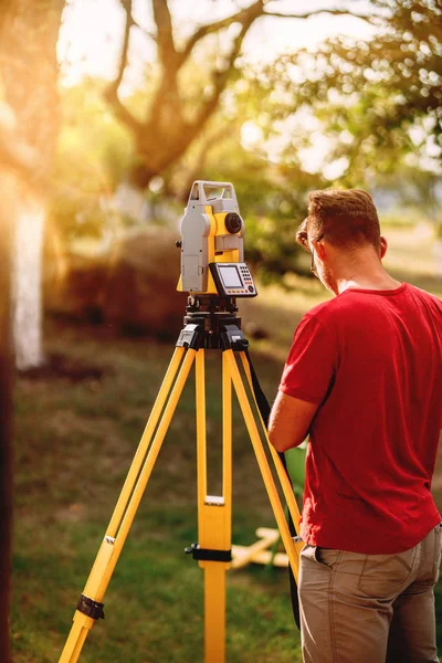 Porträtt av SURVEYOR kaukasiska ingenjör arbetar med totalstation Theodolite på Landskapsplanering Project — Stockfoto