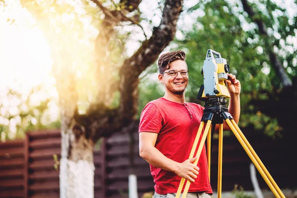 Porträtt av SURVEYOR Engineer arbetar med totalstation på trädgårds höjd — Stockfoto