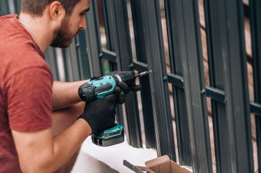 İnşaat işçisi metal elementleri kesmek için elektrikli tornavida kullanıyor. İnşaat alanı detayları
