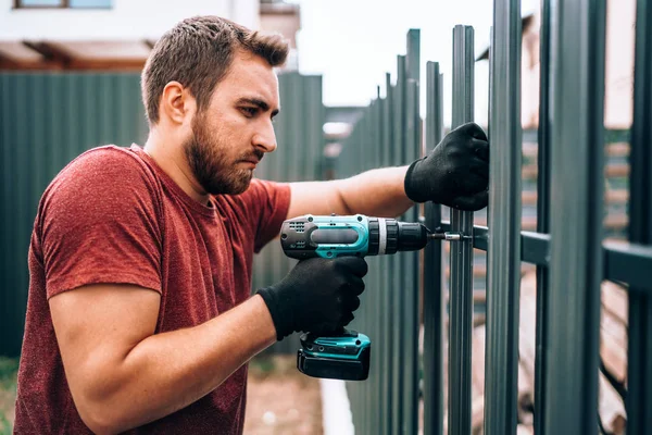 Ezermester munkás dolgozik szabadtéri fém kerítés az új ház építési telek — Stock Fotó