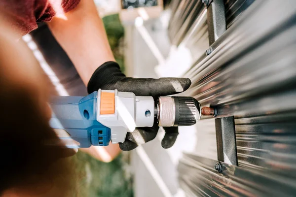 Trabalhador Handyman usando chave de fenda de cabo elétrico para fixação de parafusos em cerca de metal — Fotografia de Stock