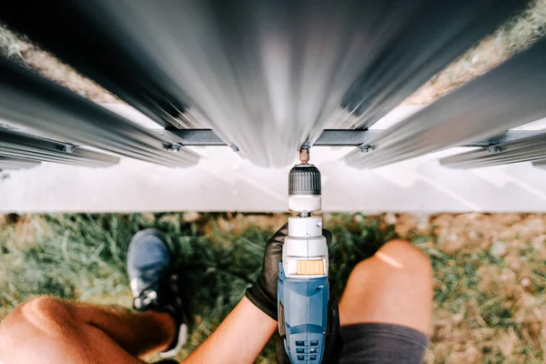 Construction worker using screwdriver and drilling screws into metal fence — Stock Photo, Image