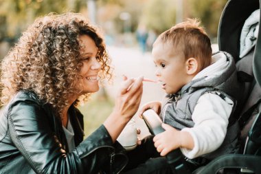 Anne konsepti - Bebek arabasında 1 yaşındaki bebeğe yoğurt veren anne portresi
