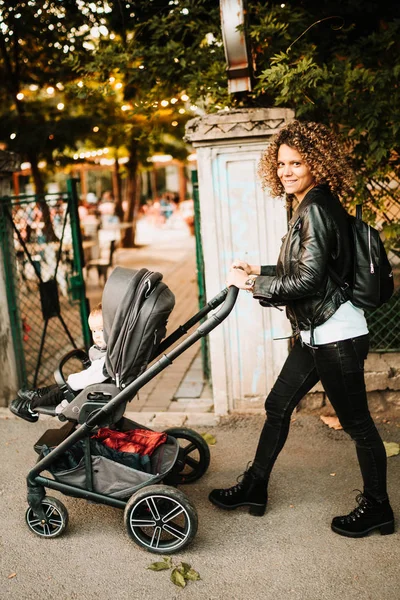 Portret de mama fericita mers pe jos copil cărucior în parc — Fotografie, imagine de stoc
