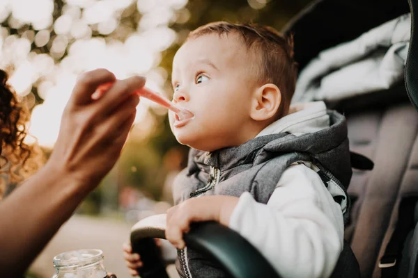 1-letnie dziecko jedzące jogurt w wózku w parku miejskim — Zdjęcie stockowe