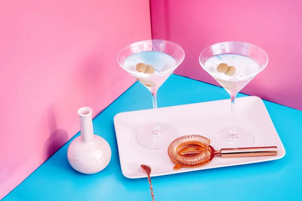 Details of Vodka Martini with olive garnish. Long drink alcoholic cocktail on pink and blue background