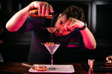 Barda zeytinli martini hazırlayan profesyonel bir barmen. Kuru votka martini, restoranda, barda ve barda servis edilen kokteyl. Uzun içki kokteyli konsepti
