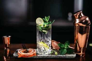 Limonlu ve naneli mojito kokteyli ve bar tezgahında cin.