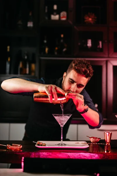 Barman creating signature drink at bar counter. Bitter dry martini with green olives cocktai