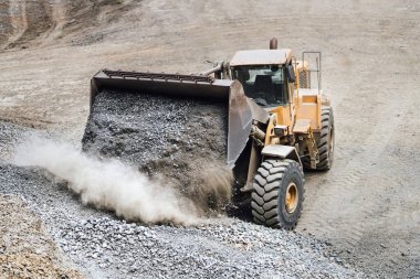 Endüstriyel ağır buldozer otoyol inşaatında çakıl taşıyor. İnşaat alanında birden fazla endüstriyel makine