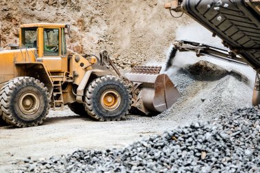 Ağır yük yük makinası açık madene taş yüklüyor, demir cevheri madenciliği detayları. Endüstriyel makineler kaya kırıcı, ezici ve çöp kamyonlarıyla çalışıyor.