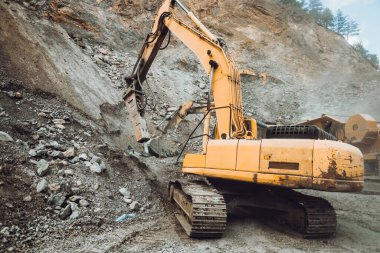 Endüstriyel kazıcı çukur kazıyor ve maden ocağı ya da inşaat alanında bir çöp kamyonuna cevher yüklüyor.