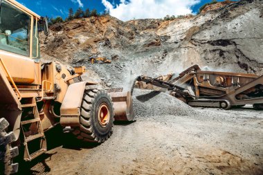 İnşaat alanında kepçeli çakıl yüklü kazıcı buldozer.