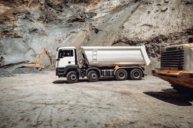 Tekerlek yükleyicisi, çakılları çöp kamyonlarına yüklüyor. Endüstri ayrıntıları - makine çalışıyor. 