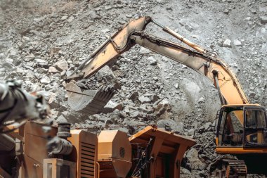 Otoyol inşaatında çalışan sanayi tipi kazıcı kaya eziciyi yüklüyor. 