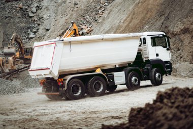 İnşaat alanında çalışan endüstriyel çöp kamyonları çakıl ve toprak yükleyip boşaltıyorlar. Ağır iş makineleri etkinliği