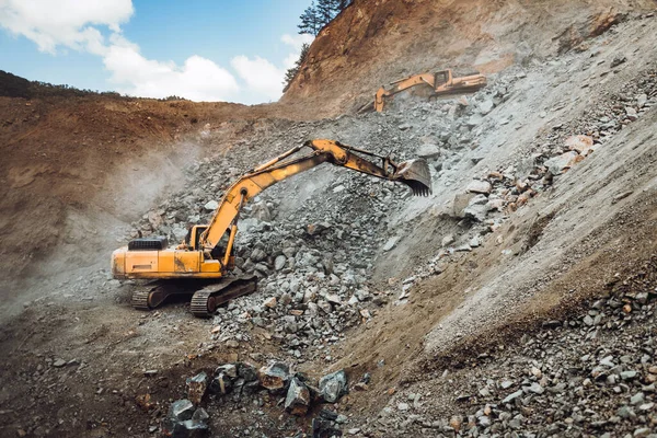 在采石场或建筑工地的垃圾车中挖掘和装载矿石的工业履带式挖掘机 机械详情 — 图库照片