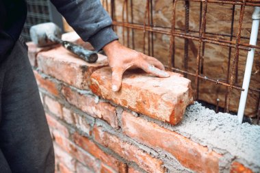 Duvarın dış duvarına tuğla döşeyen tuğla ustası işçi elleri ve aletleriyle