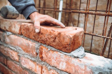 İnşaat ustası, tuğla döşeyen ve inşaat sahasına duvar ören bir işçi. El ayarlama ve tuğla yerleştirme ayrıntıları 