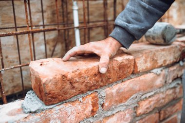 İnşaat ustası, inşaat işçisi inşaat sahasına tuğla döşeyen ve duvar ören. El ayarlama ve tuğla yerleştirme ayrıntıları 