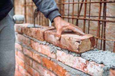 Tuğla ustası tuğlaları havan topu ile yerleştiriyor ve ayarlıyor. Dış duvar inşa eden profesyonel inşaat işçisi