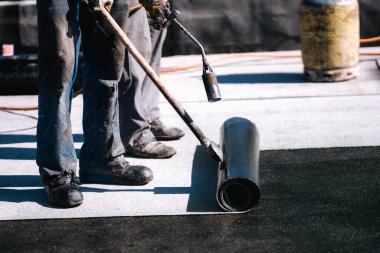 İnşaat işçileri, çatı ustaları yeni evin su geçirmez hale getirilmesi için su geçirmez zar döşüyorlar. Ev su geçirmez ve yalıtımlı