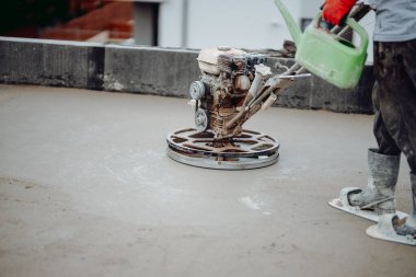 Kum ve çimento elektrikli mala kullanan işçiler inşaat alanında döşeme ve bitirme işlemleri yapıyor. 