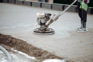 İnşaat işçisi beton tornavidayı güç malası makinesiyle bitiriyor, beton perdeleniyor ve düzleştiriyor.