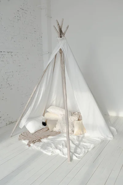 White wigwam with fluffy pillows on floor