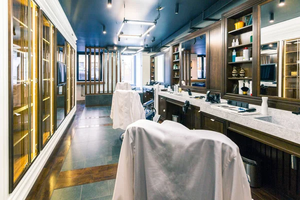 luxury barber shop interior, blue expensive furniture, wood trim, fashionable black ceiling, white robes on the backs of armchairs