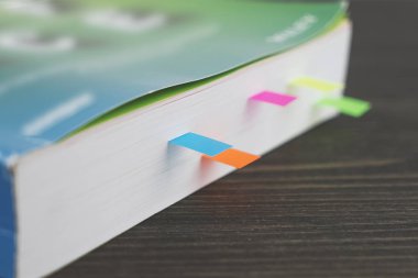 Ahşap masa üzerinde renkli yer imleri ile kalın bir kitap kenarına