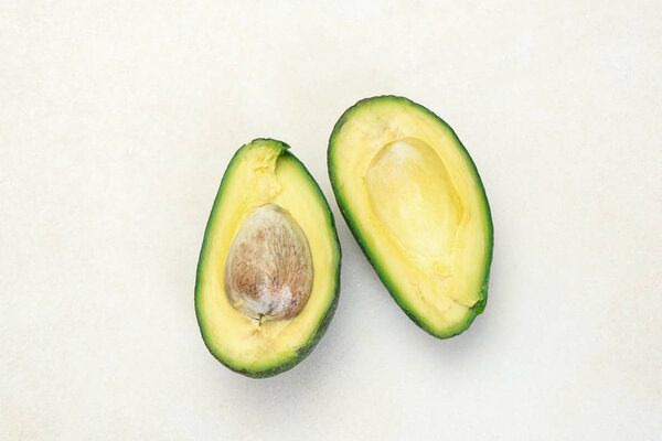 Close up of half sliced ripe avocado on white table