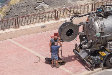 Xghajra, Malta - 05 Temmuz 2018: İki işçi Servisi pompa dökümleri kapağı üzerinden dışarı pompalama kanalizasyon